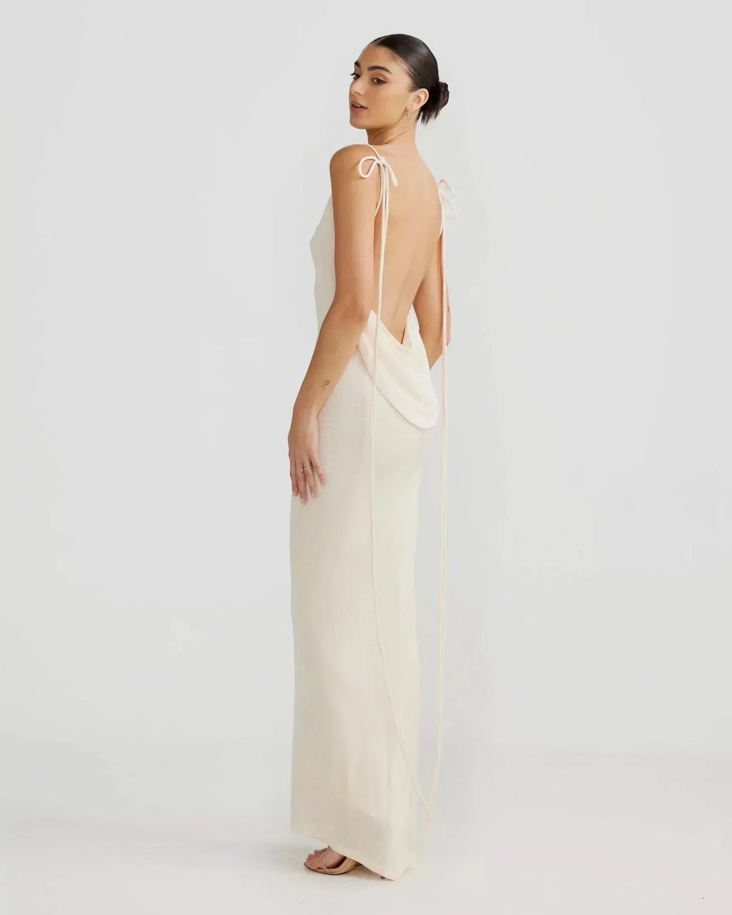 Women cream sleeveless cowl neck maxi dress with open back design, side profile view