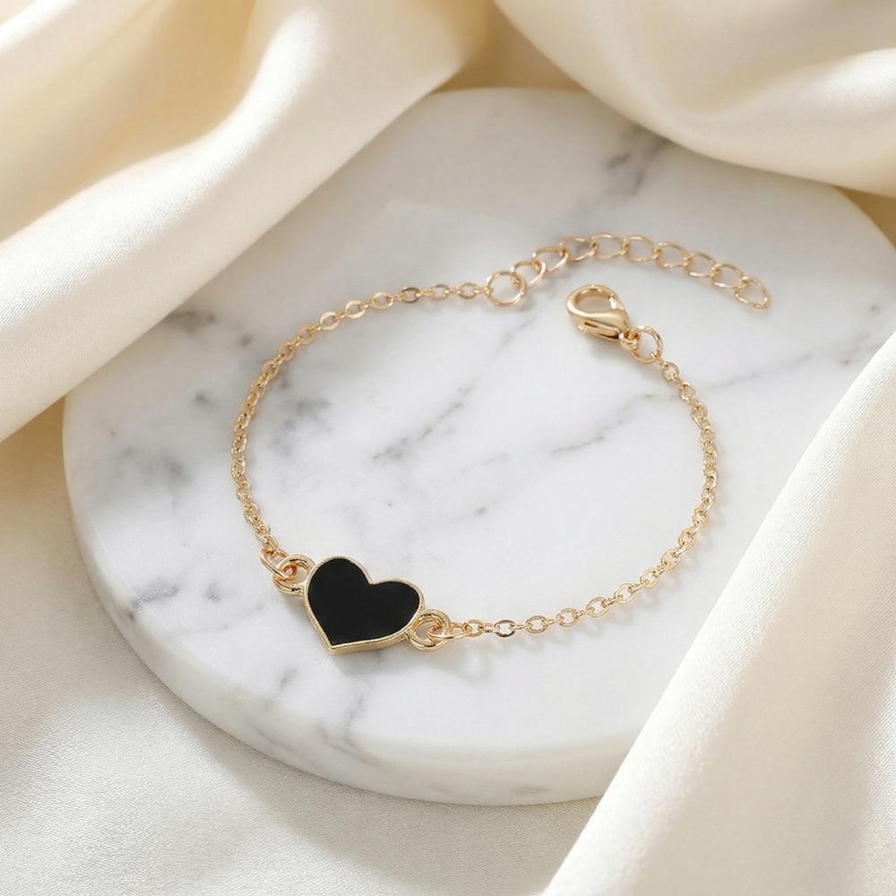 Women's gold chain bracelet with black heart charm and gold bezel setting
