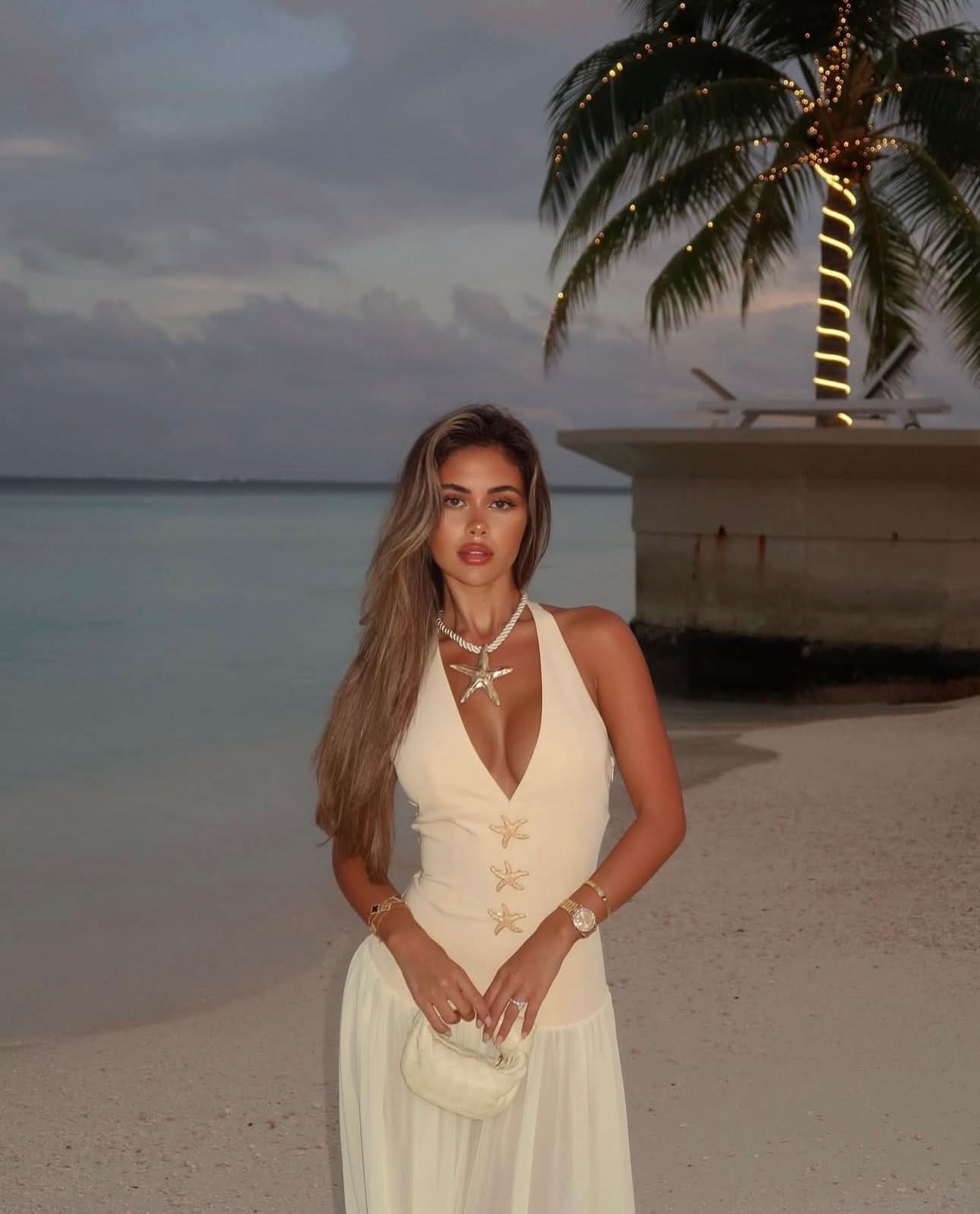 Women halter maxi dress with starfish details worn on beach at sunset with flowing skirt