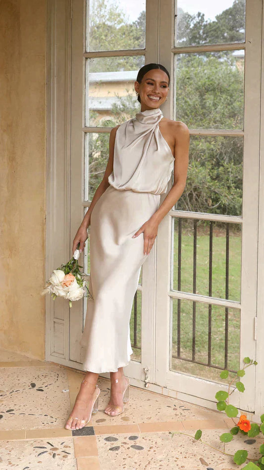Women cream halter midi dress with draped neckline standing by window