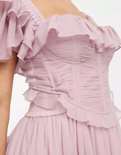 Close-up of ruched corset bodice and ruffle neckline on pink midi dress