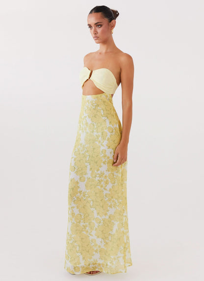 Side view of women yellow strapless maxi dress with cutout detail and flowing skirt