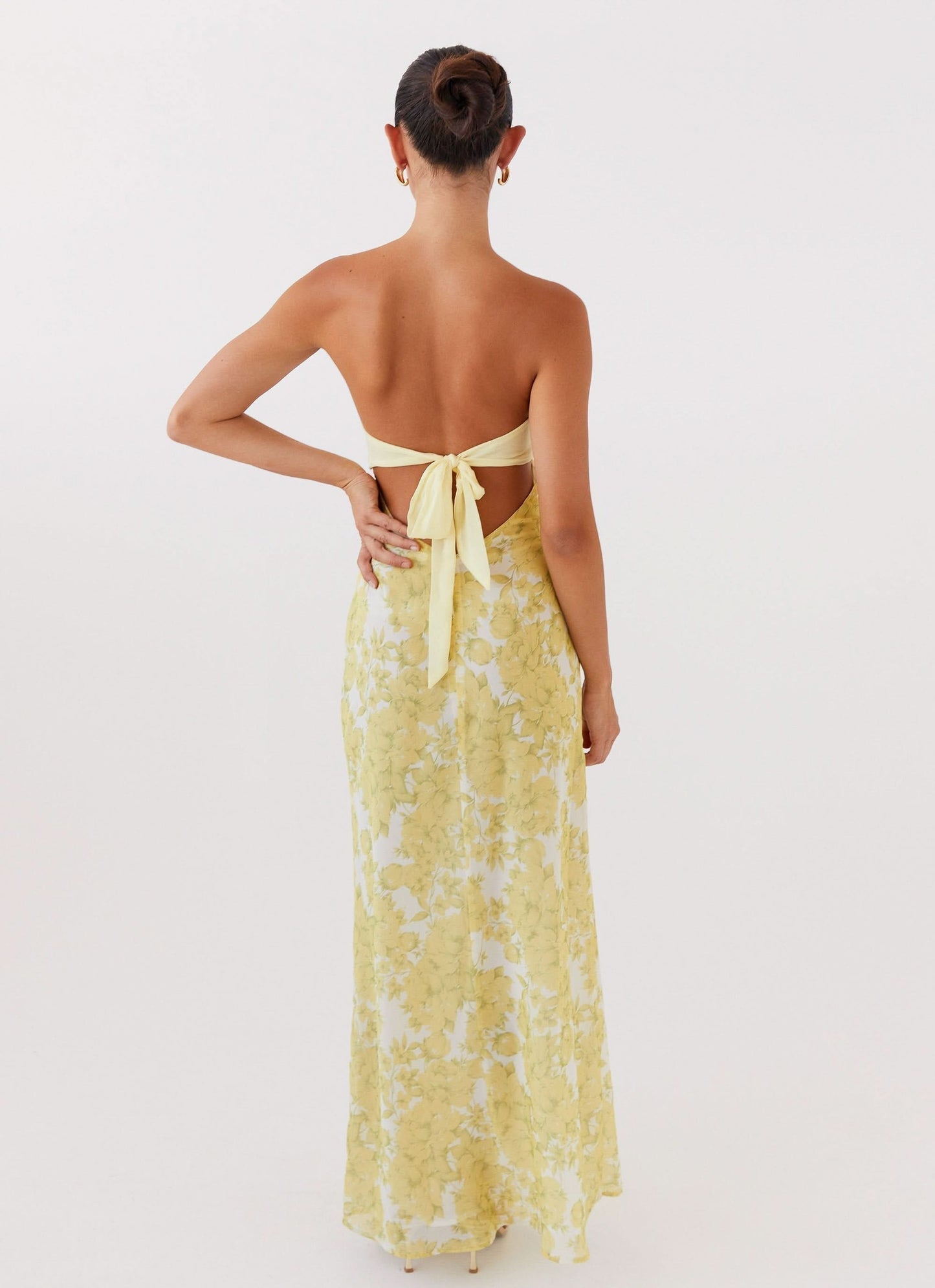 Back view of women's yellow floral maxi dress showing tie closure and flowing silhouette