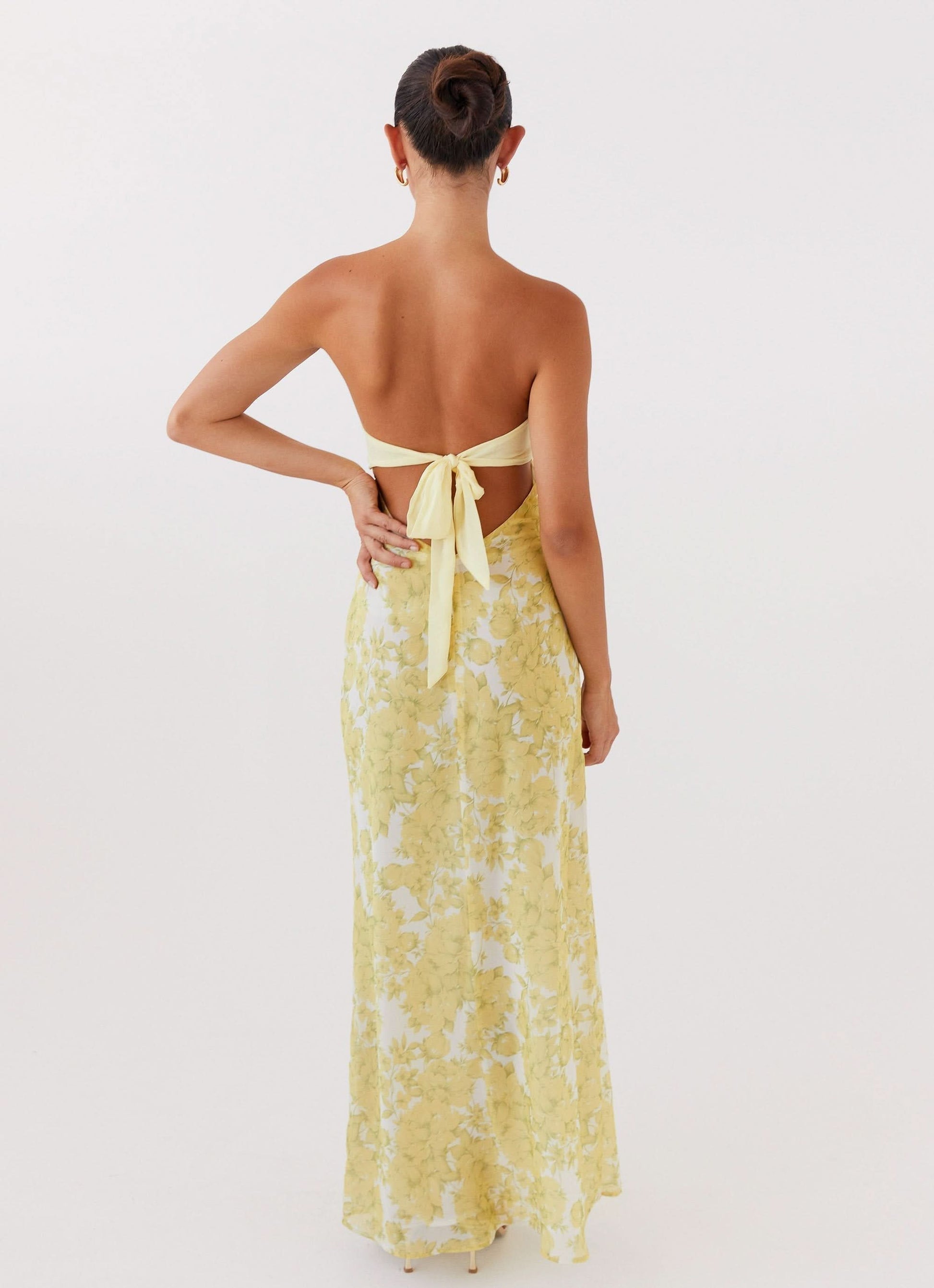 Back view of women's yellow floral maxi dress showing tie closure and flowing silhouette