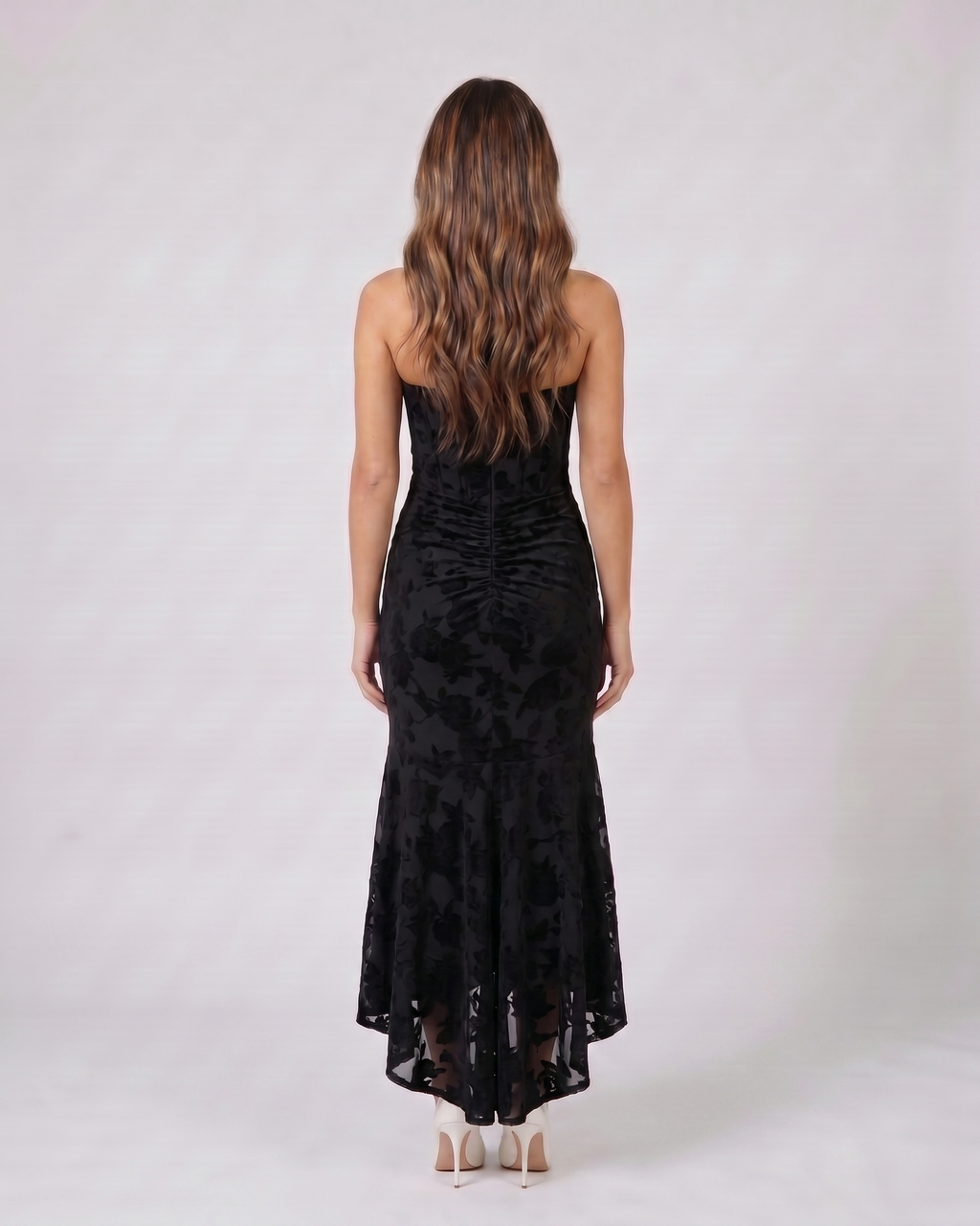 Back view of black floral jacquard strapless high low maxi dress showing solid back with vertical ruching and concealed zipper closure