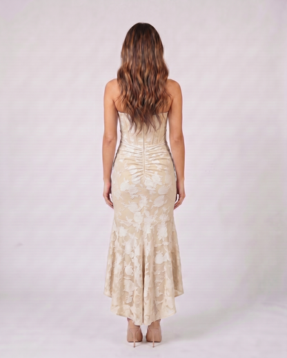 Back view of beige floral jacquard strapless high low maxi dress showing solid back with vertical ruching and concealed zipper closure