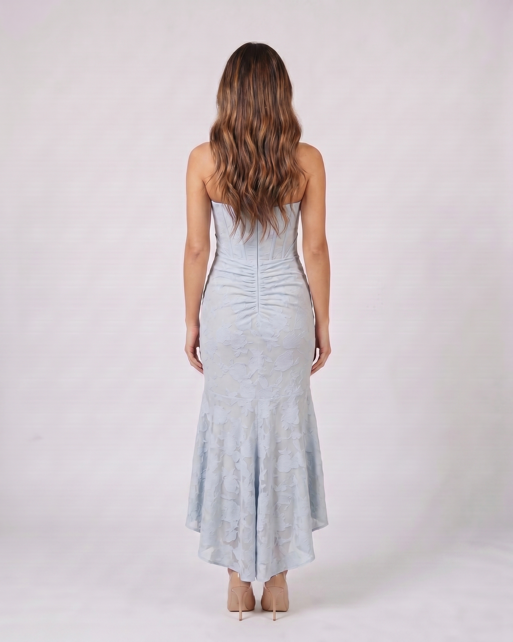 Back view of blue floral jacquard strapless high low maxi dress showing solid back with vertical ruching and concealed zipper closure