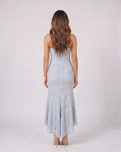 Back view of blue floral jacquard strapless high low maxi dress showing solid back with vertical ruching and concealed zipper closure