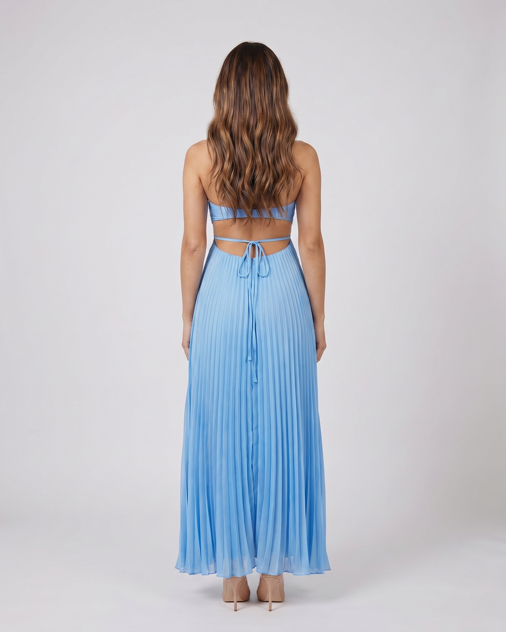 Back view of blue halter pleated with cutout maxi dress showing open back with horizontal mid-back strap and criss-cross tie straps at lower back
