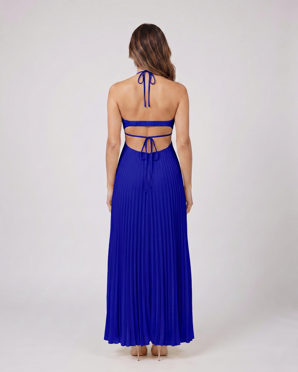 Back view of dark blue halter pleated with cutout maxi dress showing open back with horizontal mid-back strap and criss-cross tie straps at lower back