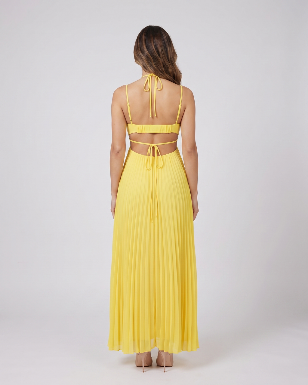Back view of yellow halter pleated with cutout maxi dress showing open back with horizontal mid-back strap and criss-cross tie straps at lower back