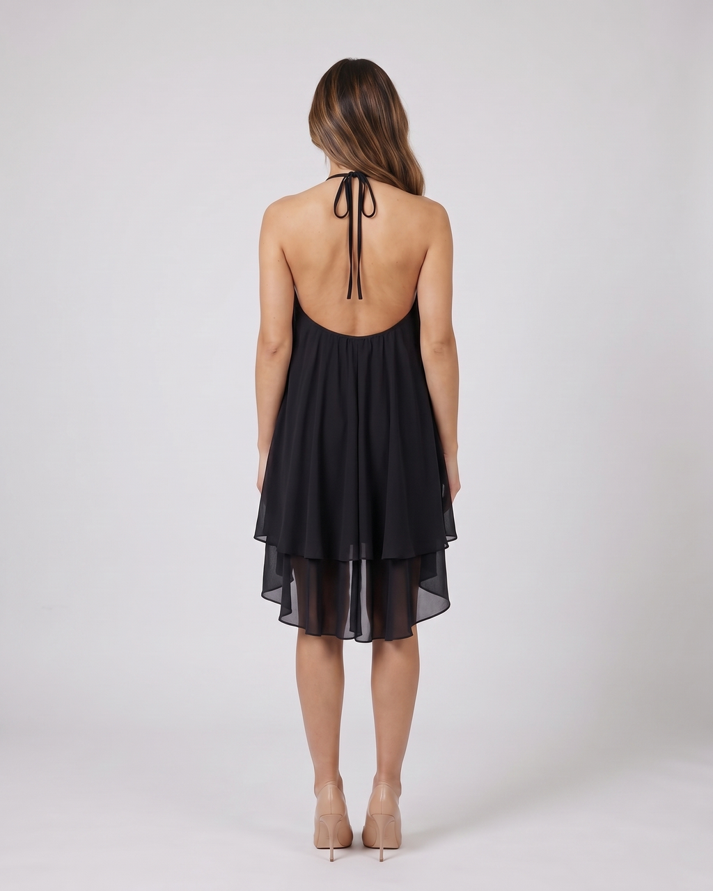 Back view of black halter sleeveless asymmetric mini dress showing open back with halter tie-back