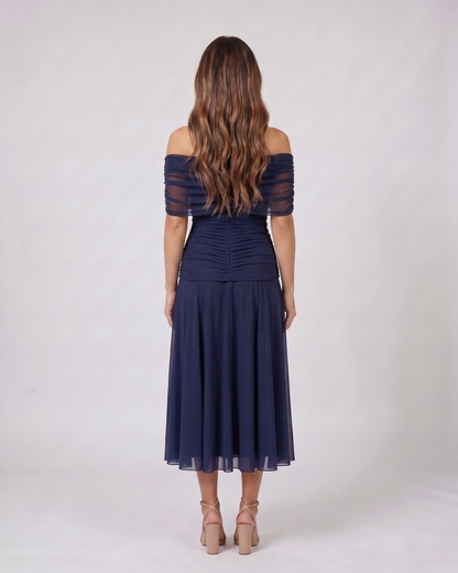 Back view of blue off shoulder ruched midi dress showing solid back with draped and ruched details