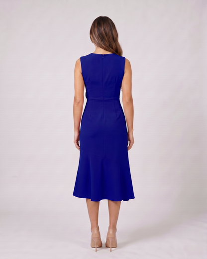 Back view of navy blue sleeveless asymmetric draped midi dress showing solid back with center back zipper closure
