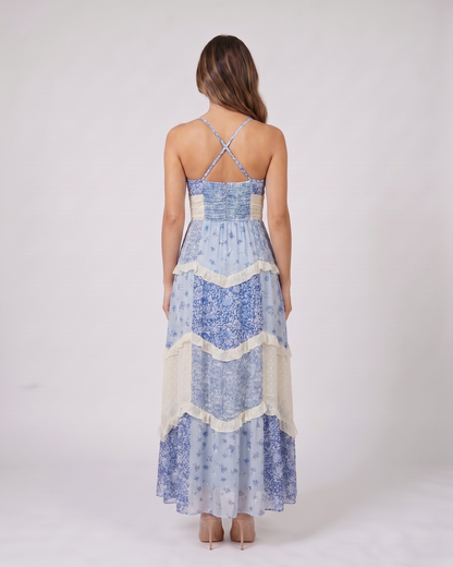 Back view of blue wedding guest floral v neck maxi dress showing open back with criss-cross X-straps and smocked upper back panel