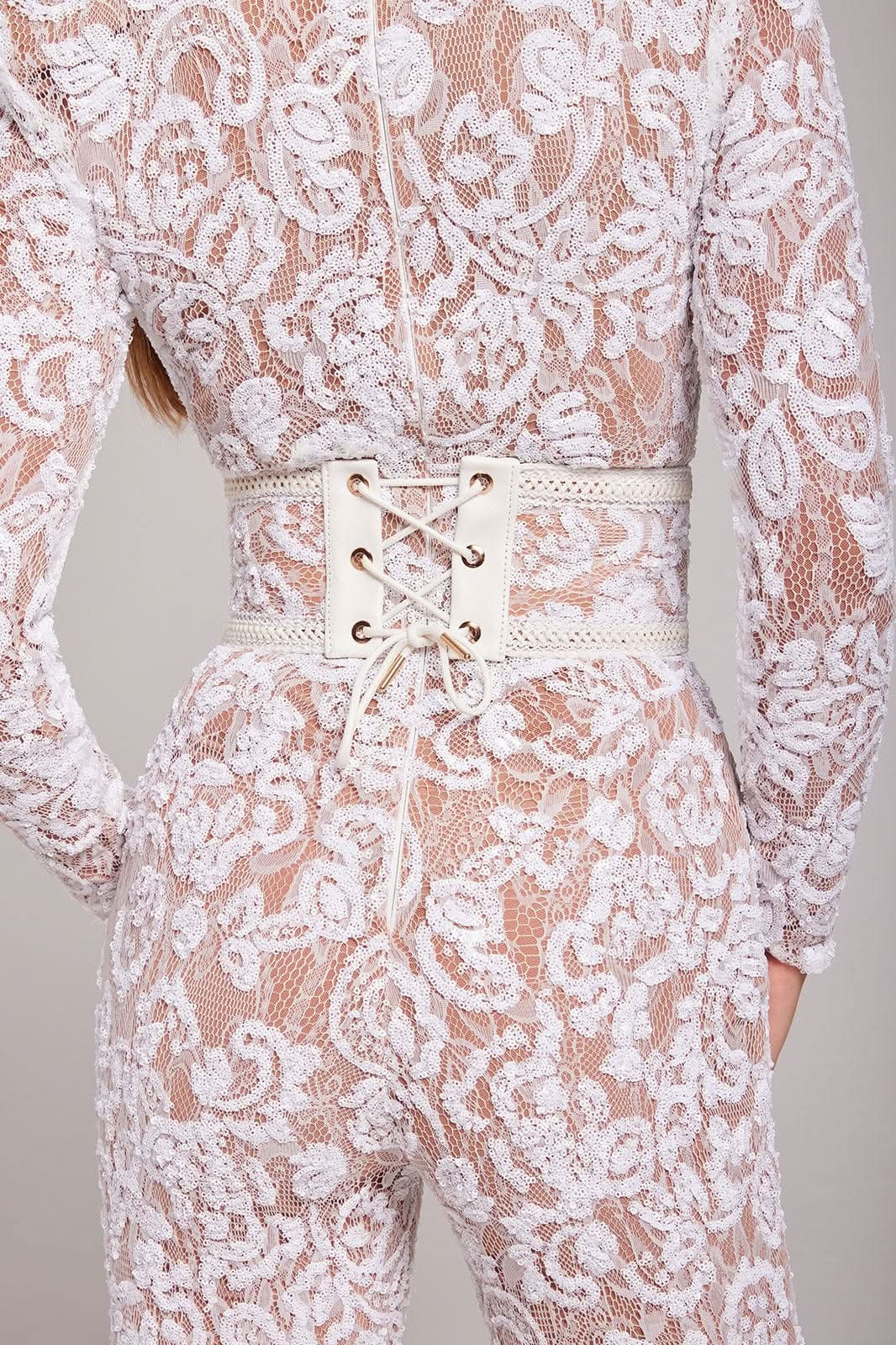 Detail of cream lace-up belt and white lace fabric on wide leg jumpsuit